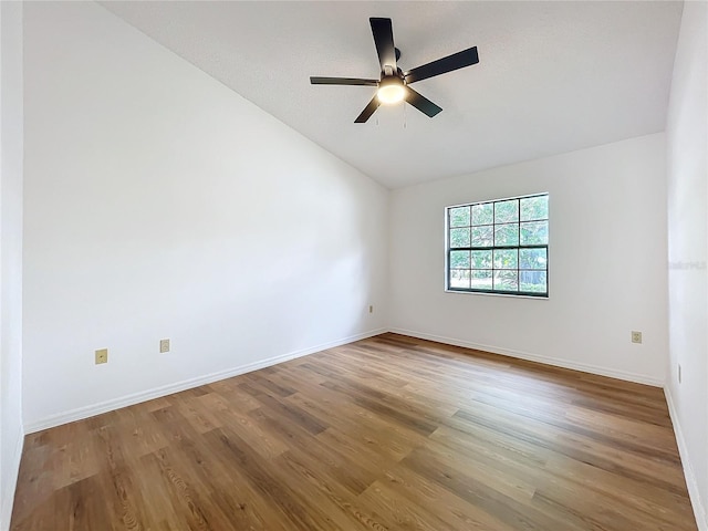 spare room with lofted ceiling, wood finished floors, a ceiling fan, and baseboards