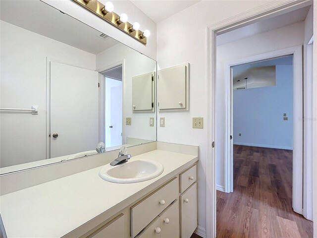 bathroom featuring visible vents, baseboards, wood finished floors, and vanity