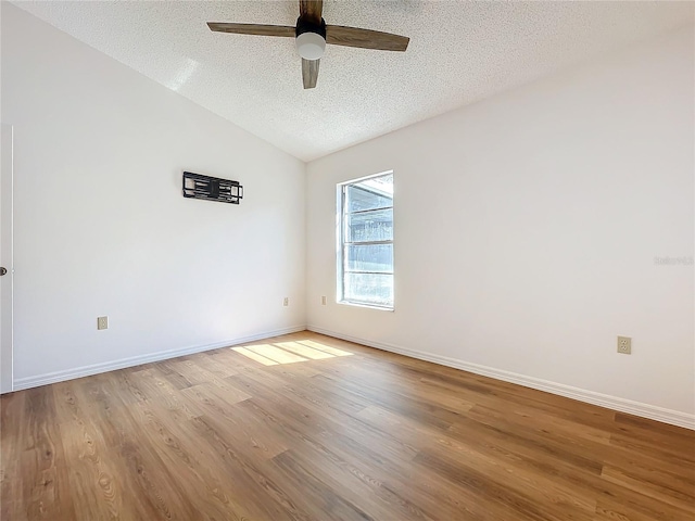 empty room featuring baseboards, lofted ceiling, ceiling fan, wood finished floors, and a textured ceiling