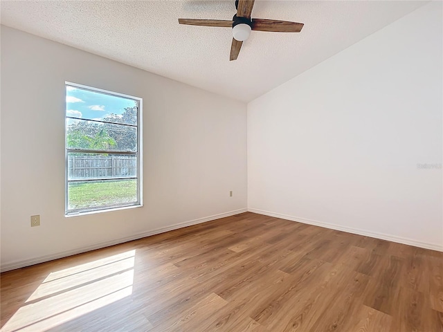 spare room with a textured ceiling, ceiling fan, light wood finished floors, and baseboards