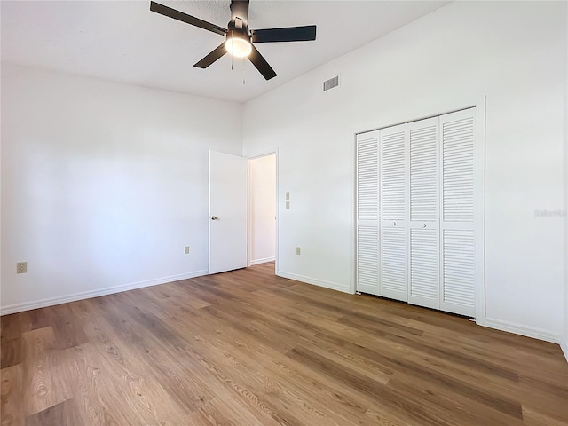 unfurnished bedroom with baseboards, visible vents, ceiling fan, wood finished floors, and a closet