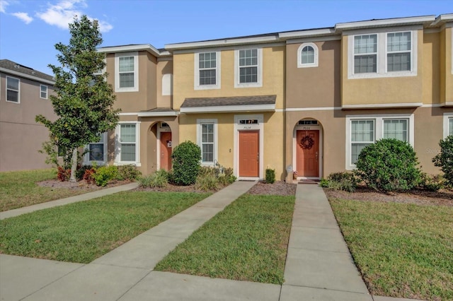 view of property with a front yard and stucco siding