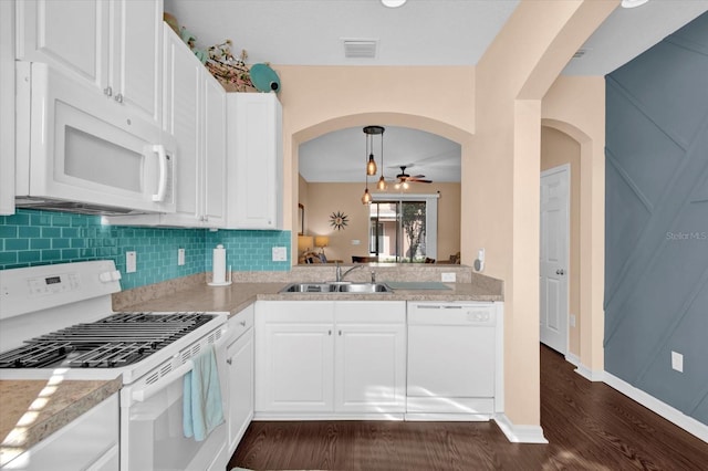 kitchen featuring white appliances, tasteful backsplash, visible vents, arched walkways, and a sink