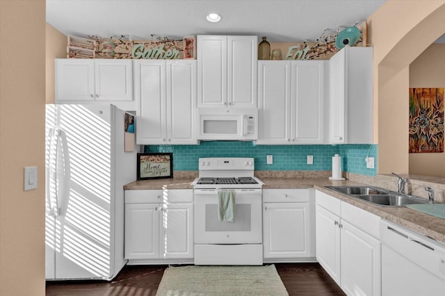 kitchen featuring white appliances, a sink, white cabinets, light countertops, and tasteful backsplash