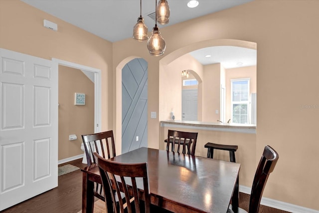 dining area featuring arched walkways, dark wood finished floors, baseboards, and recessed lighting