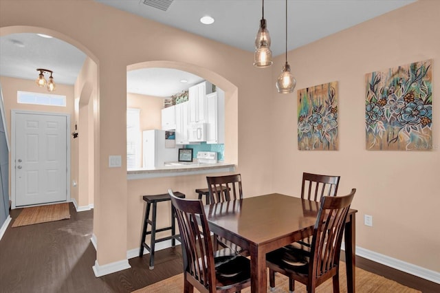 dining room featuring visible vents, baseboards, dark wood-style flooring, and recessed lighting