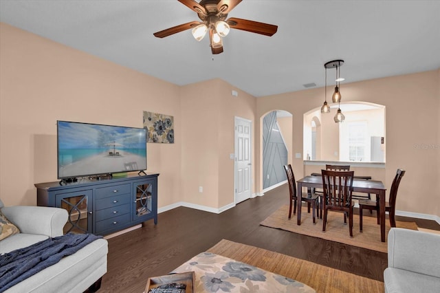 living area with a ceiling fan, arched walkways, baseboards, and wood finished floors