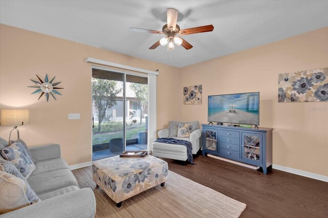 living room with ceiling fan, baseboards, and wood finished floors