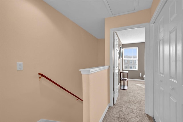 hallway with carpet floors, baseboards, and an upstairs landing