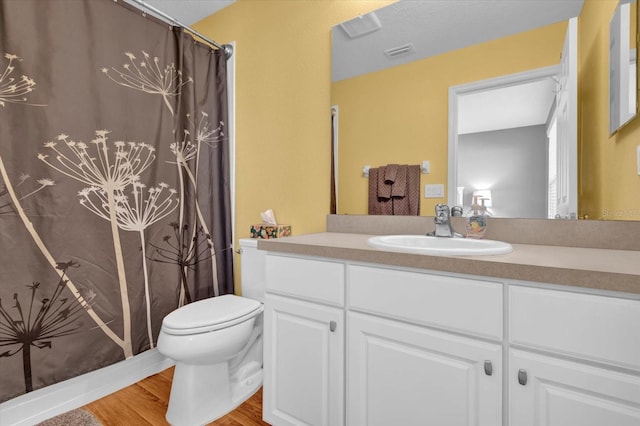 bathroom with curtained shower, toilet, wood finished floors, vanity, and visible vents