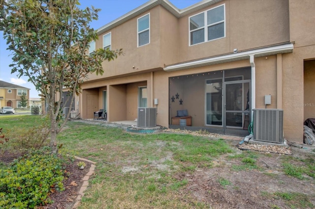 back of property with central AC, a lawn, and stucco siding