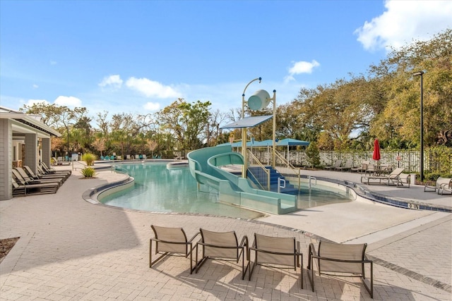 pool featuring a water play area, a patio area, and fence