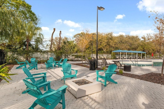 view of property's community featuring an outdoor fire pit, a patio, and fence