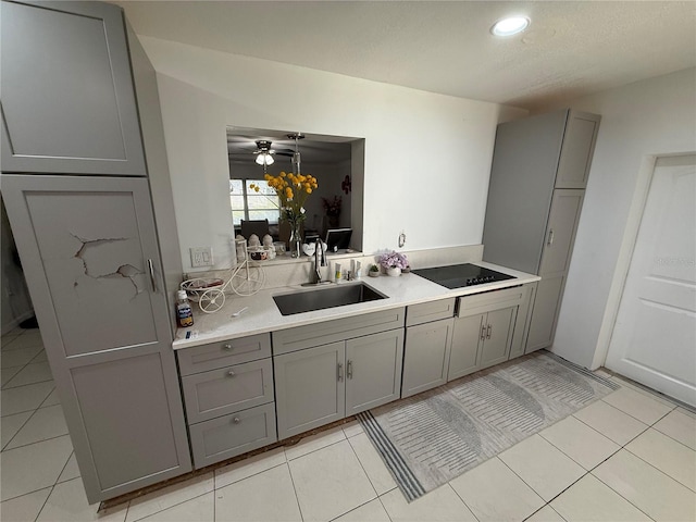 kitchen featuring light tile patterned floors, black electric cooktop, gray cabinets, and a sink