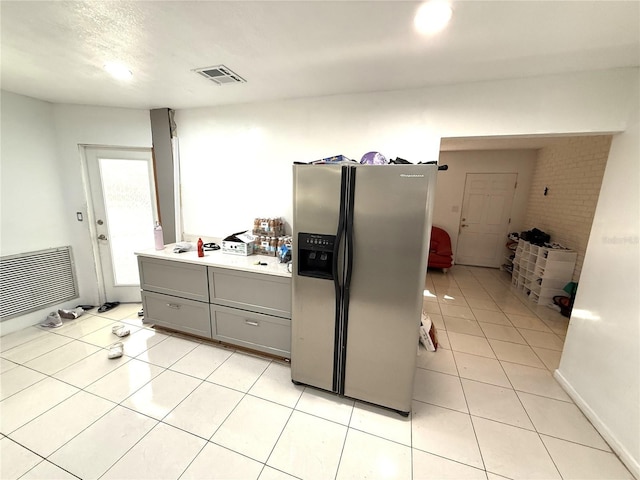 kitchen with stainless steel refrigerator with ice dispenser, gray cabinets, light countertops, visible vents, and light tile patterned flooring