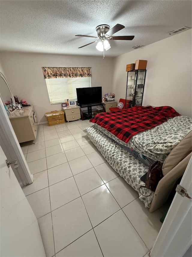 bedroom featuring light tile patterned floors, ceiling fan, a textured ceiling, and visible vents