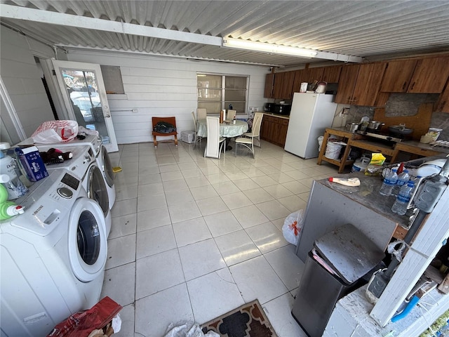 kitchen featuring brown cabinets, light tile patterned floors, light countertops, freestanding refrigerator, and independent washer and dryer