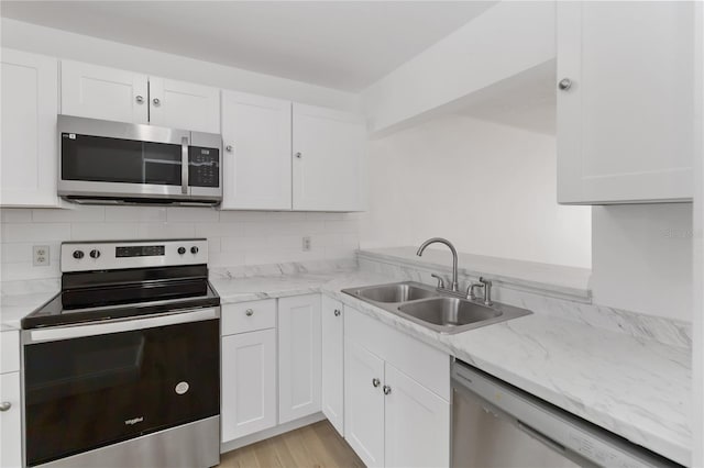 kitchen featuring tasteful backsplash, appliances with stainless steel finishes, a sink, and white cabinets