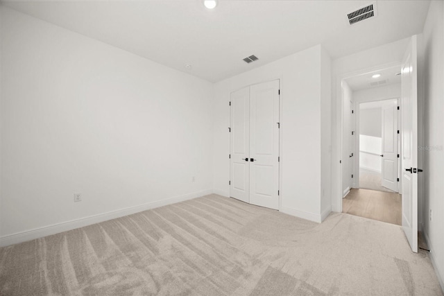 unfurnished bedroom with a closet, carpet, visible vents, and baseboards