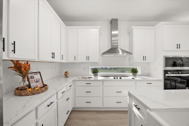 kitchen with electric cooktop, oven, wall chimney exhaust hood, and white cabinetry