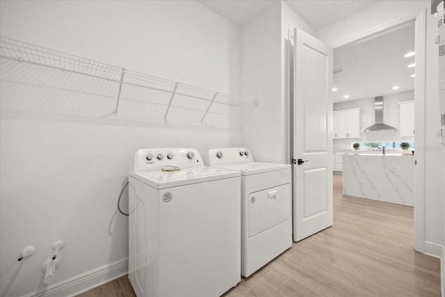 laundry room with laundry area, baseboards, independent washer and dryer, and light wood finished floors