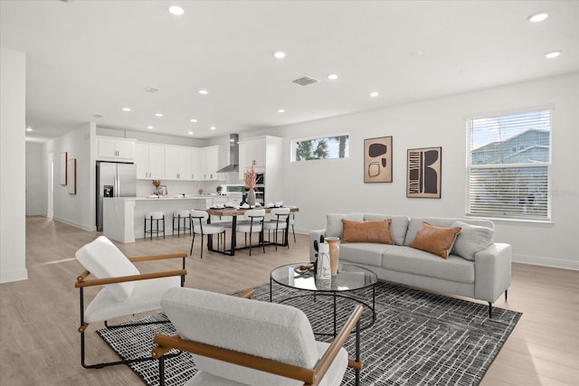 living area featuring light wood-style floors, recessed lighting, and a healthy amount of sunlight