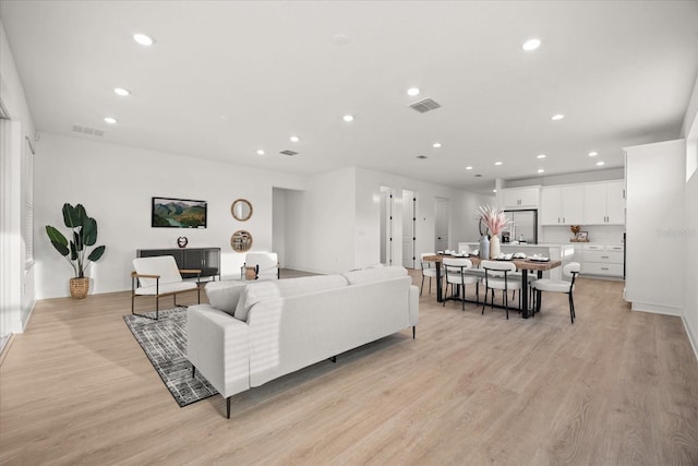 living area with recessed lighting, visible vents, and light wood finished floors