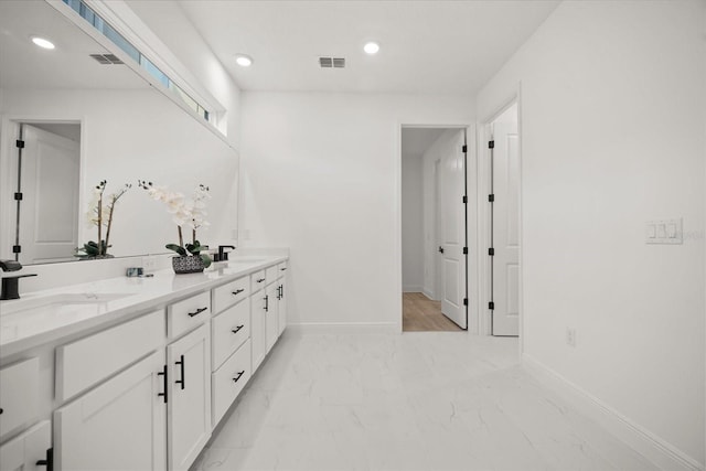 bathroom with marble finish floor, baseboards, visible vents, and a sink