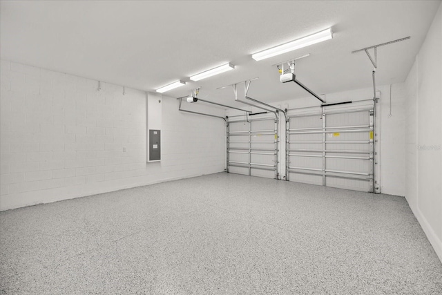 garage featuring concrete block wall, electric panel, and a garage door opener