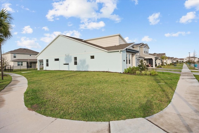 view of property exterior with a residential view, fence, a lawn, and stucco siding