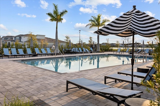 community pool with a patio and fence