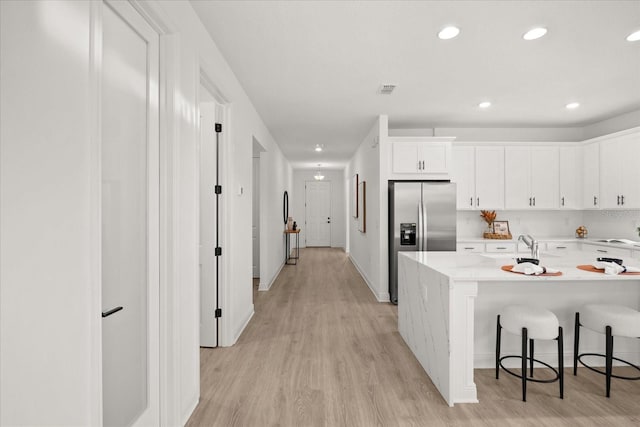 19307 Banfield Pl, Orlando, FL 32827 - kitchen featuring a kitchen breakfast bar, white cabinetry, light wood finished floors, and stainless steel fridge