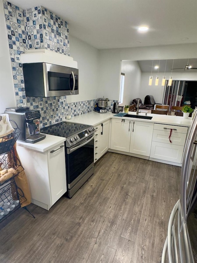 kitchen with appliances with stainless steel finishes, white cabinets, dark wood-style flooring, and light countertops