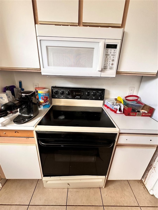 4954 Luna Negra Dr, Orlando, FL 32811 - kitchen featuring light countertops, electric range oven, white microwave, white cabinetry, and light tile patterned flooring