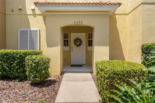 doorway to property with a tiled roof and stucco siding