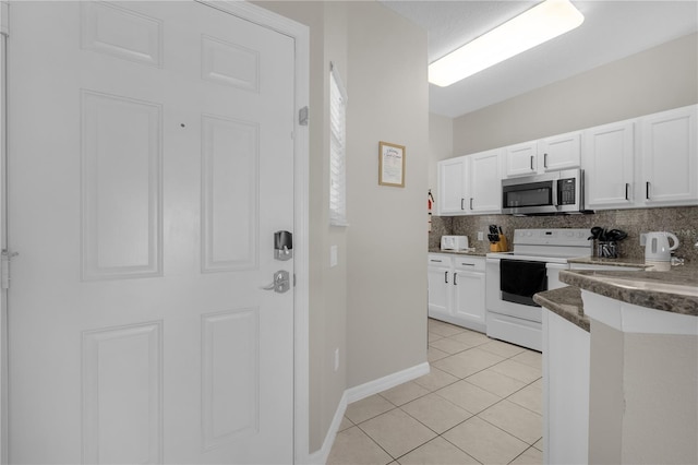 kitchen featuring white range with electric stovetop, light tile patterned floors, stainless steel microwave, decorative backsplash, and white cabinets