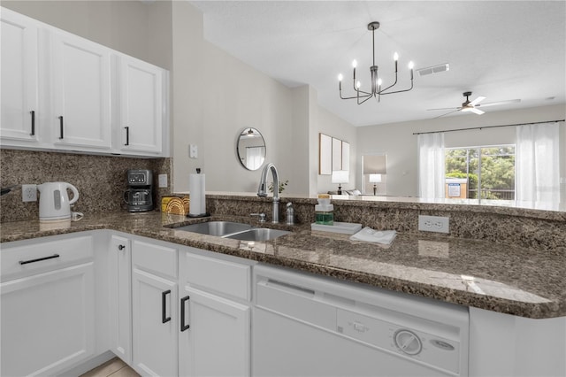 kitchen featuring dishwasher, dark stone countertops, a sink, and white cabinets