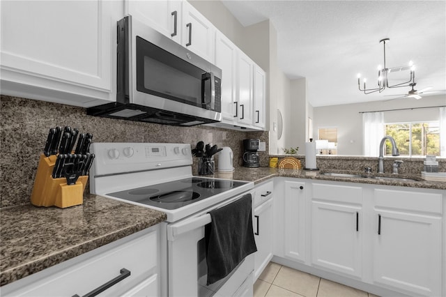 kitchen with light tile patterned floors, white range with electric cooktop, decorative backsplash, stainless steel microwave, and a sink