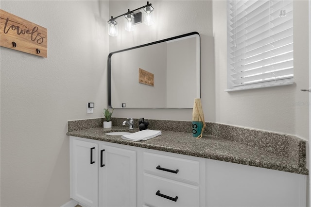 bathroom with a textured wall and vanity