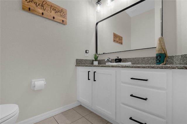 bathroom featuring toilet, vanity, baseboards, and tile patterned floors