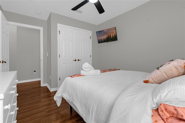 bedroom featuring dark wood-style flooring, a closet, visible vents, a ceiling fan, and baseboards