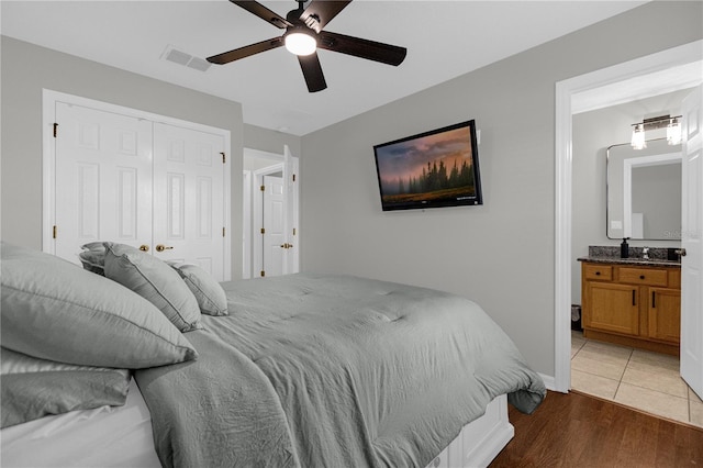 bedroom featuring visible vents, ensuite bath, ceiling fan, wood finished floors, and a closet