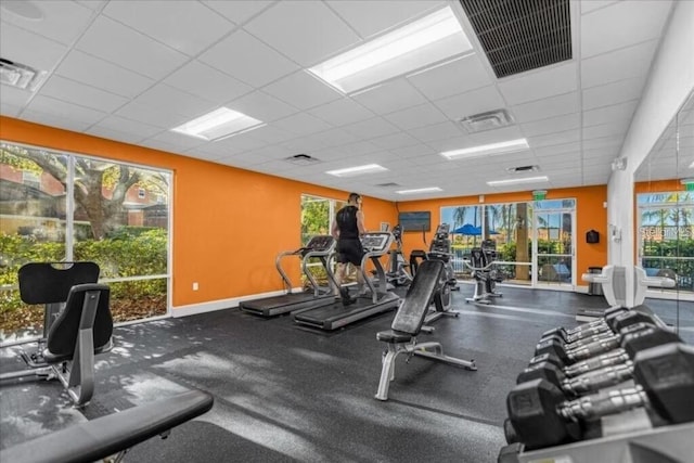 gym with a paneled ceiling, visible vents, and a wealth of natural light