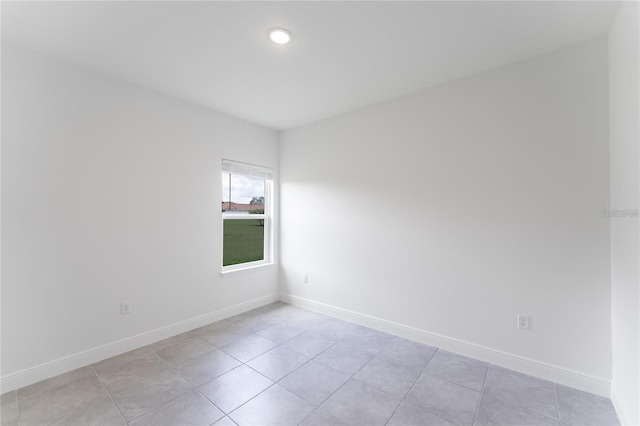 spare room featuring light tile patterned floors and baseboards