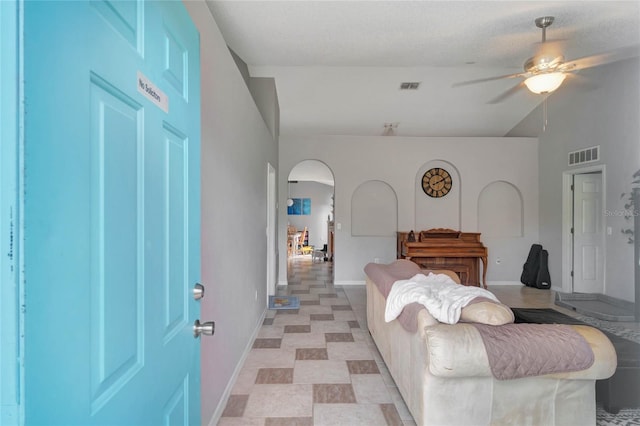 living room with arched walkways, a ceiling fan, visible vents, and baseboards