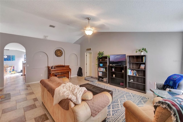 living area featuring arched walkways, vaulted ceiling, a textured ceiling, and visible vents