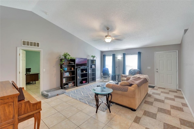 living room with lofted ceiling, light tile patterned floors, a textured ceiling, visible vents, and a ceiling fan