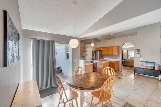 dining space featuring arched walkways, light tile patterned floors, vaulted ceiling, and a textured ceiling