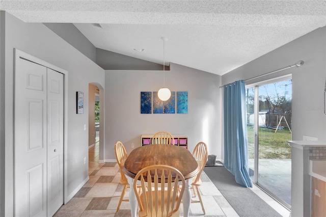 dining area featuring lofted ceiling, baseboards, arched walkways, and a textured ceiling