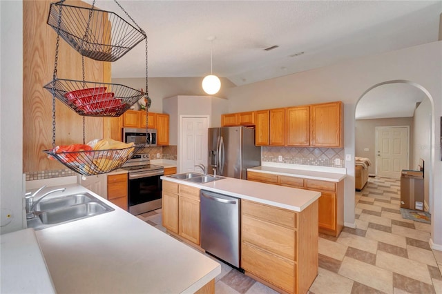 kitchen with arched walkways, light countertops, appliances with stainless steel finishes, and a sink